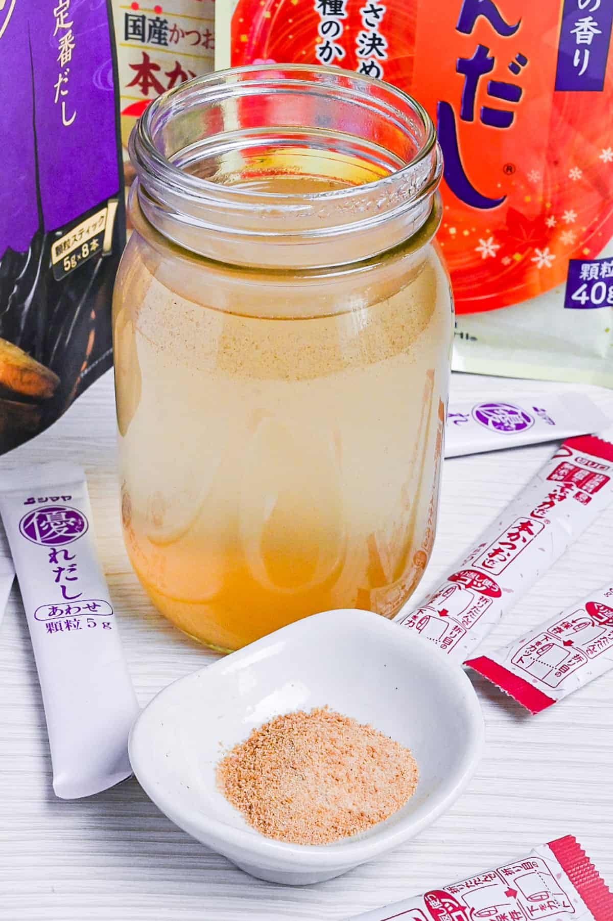 dashi made with granules in a jar surrounded by various packs of dashi granules