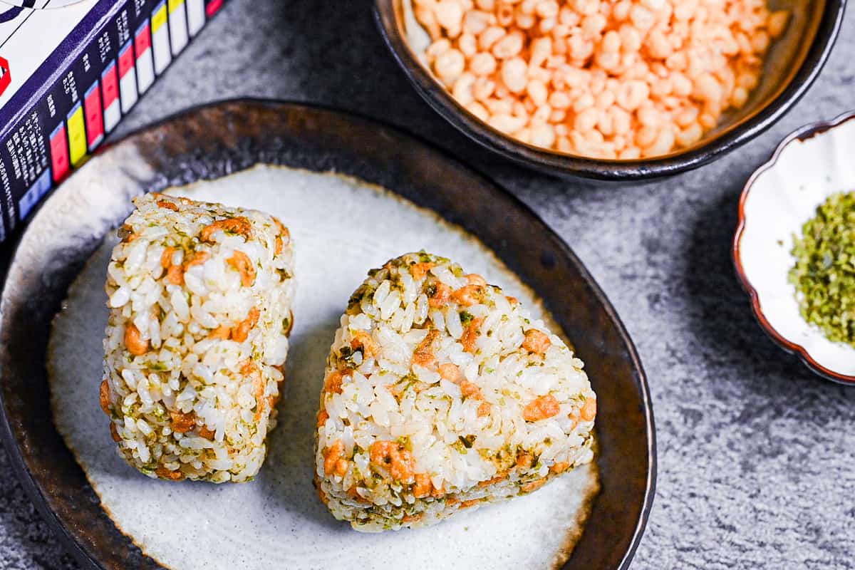 two devil's onigiris made with tempura flakes and aonori on a gray plate with a brown border