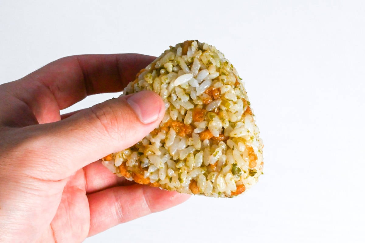 a hand holding up devil's onigiri with a white background