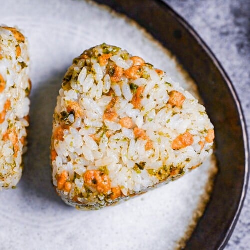 devil's onigiri made with tempura flakes and aonori on a gray plate with a brown border