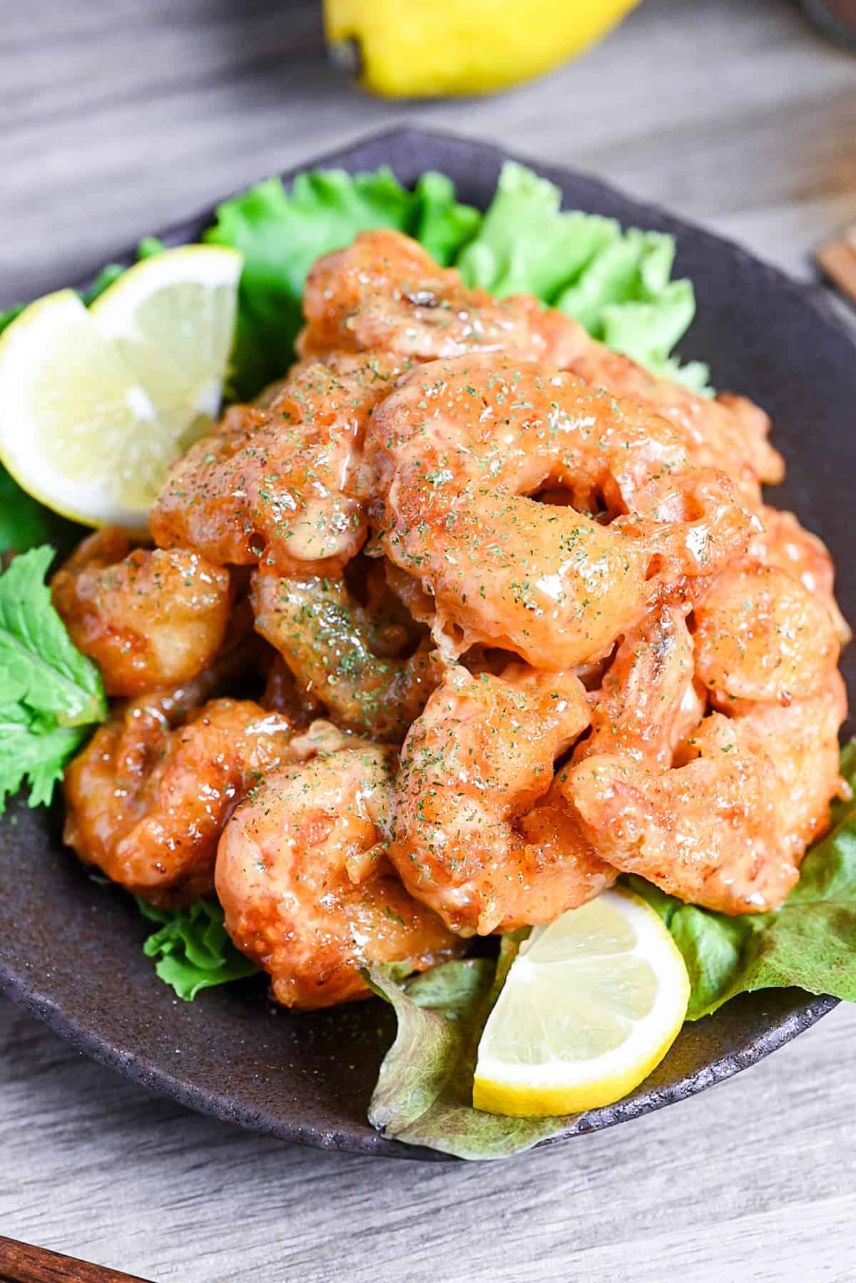 Ebi Mayo (Fried Shrimp in Mayonnaise Sauce) on a brown plate with salad and lemon wedges