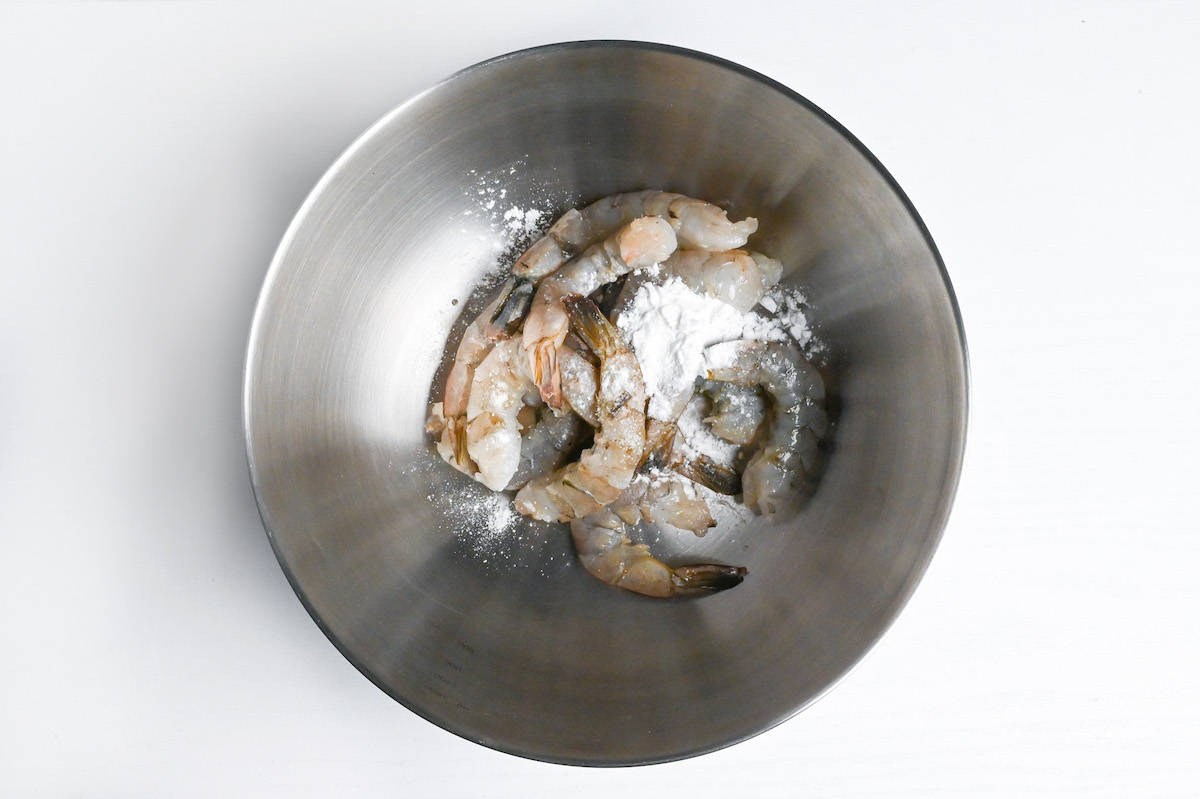 washing raw shrimps in a steel bowl with starch
