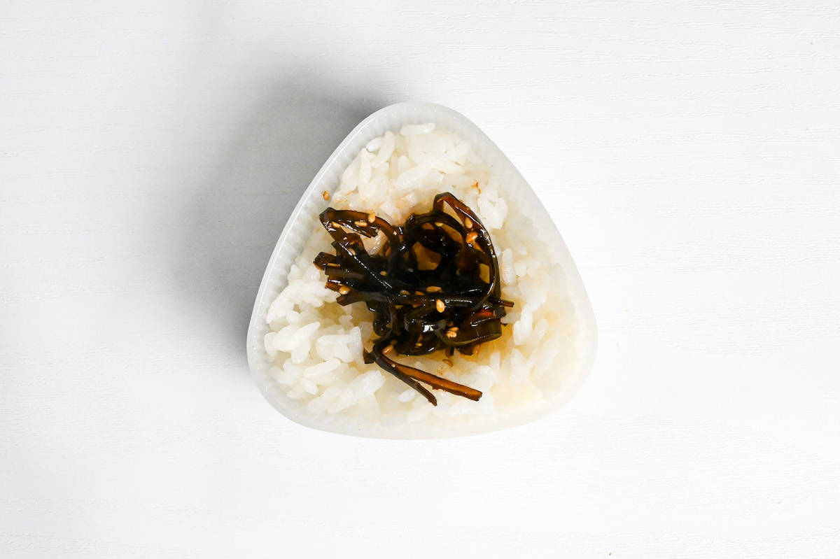 rice in an onigiri (rice ball) mold with kombu tsukudani in the center