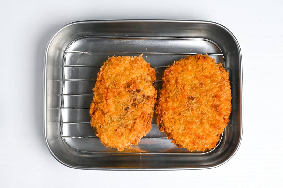 two deep fried korokke draining on a wire rack