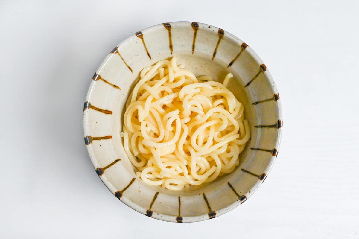 udon noodles in a beige striped bowl