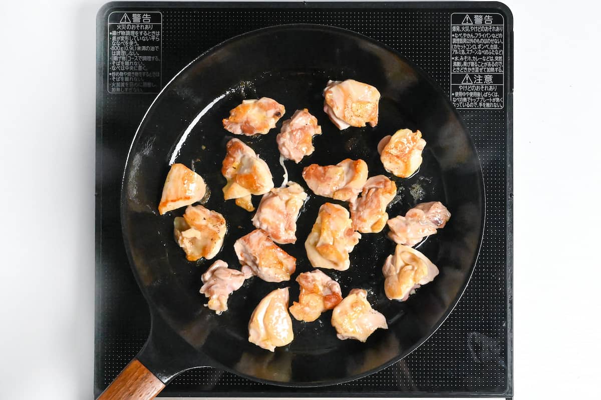 browned chicken thigh pieces in a frying pan