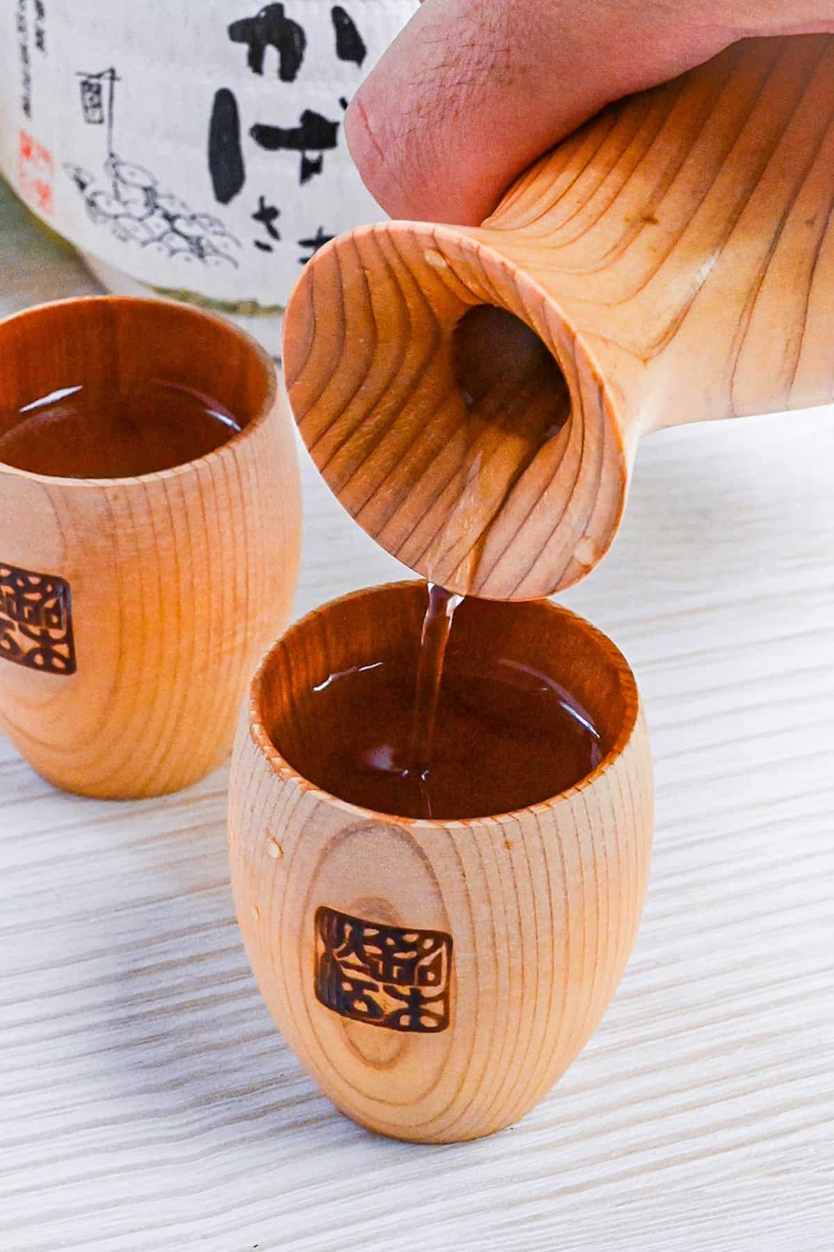 pouring sake into a wooden sake cup