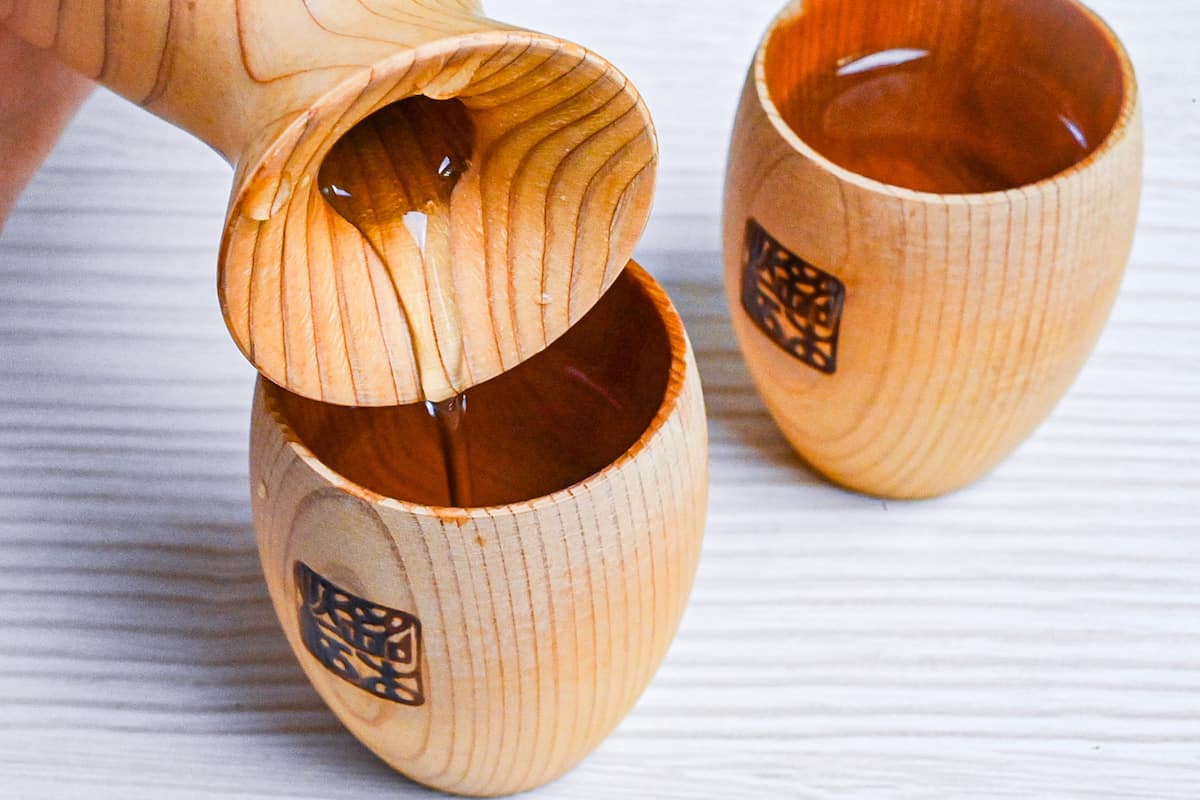 pouring sake into a wooden sake cup