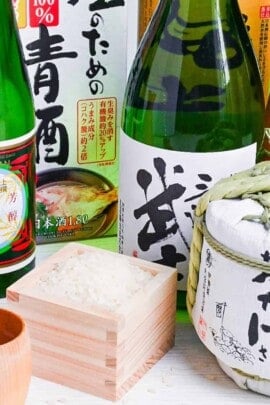 bottles of sake with a box of rice and a cup of sake