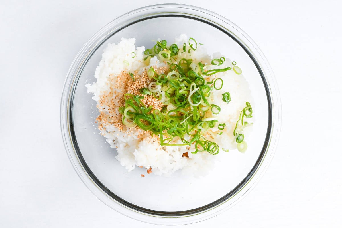mixing salmon flakes with rice, sesame seeds and green onions