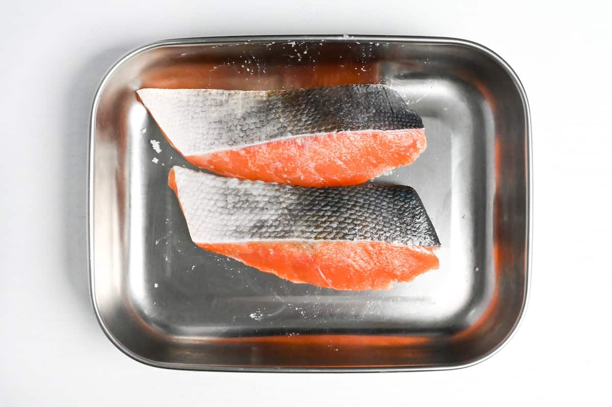 salmon fillets in a steel container sprinkled with salt