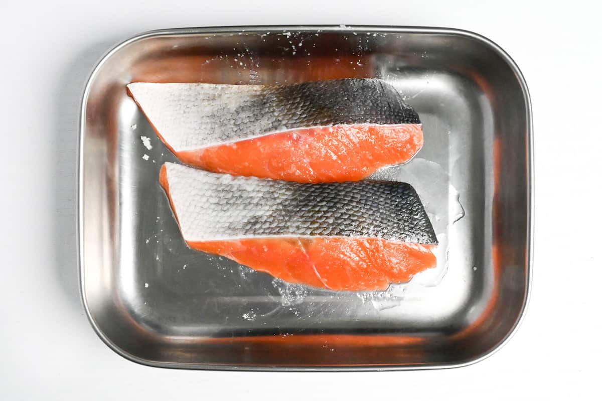 salmon fillets in a container drizzled with sake