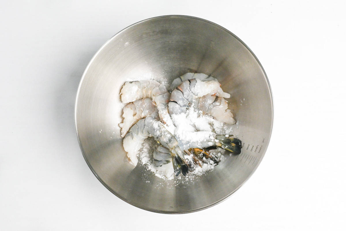 coating shrimps with flour in a mixing bowl