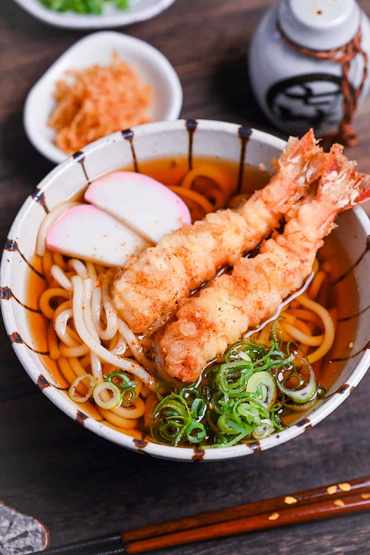 Ebiten Udon - Homemade udon noodle soup in a stripy bowl topped with kamaboko, green onion and tempura shrimp