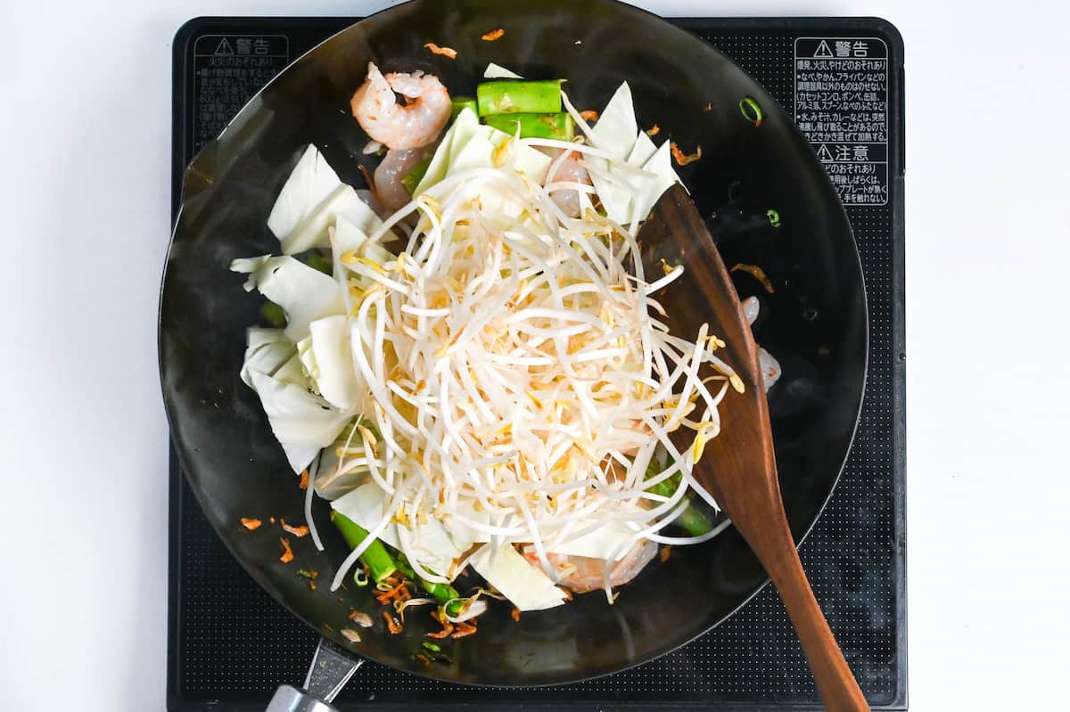 frying cabbage and beansprouts with other shrimp yaki udon ingredients in a pan