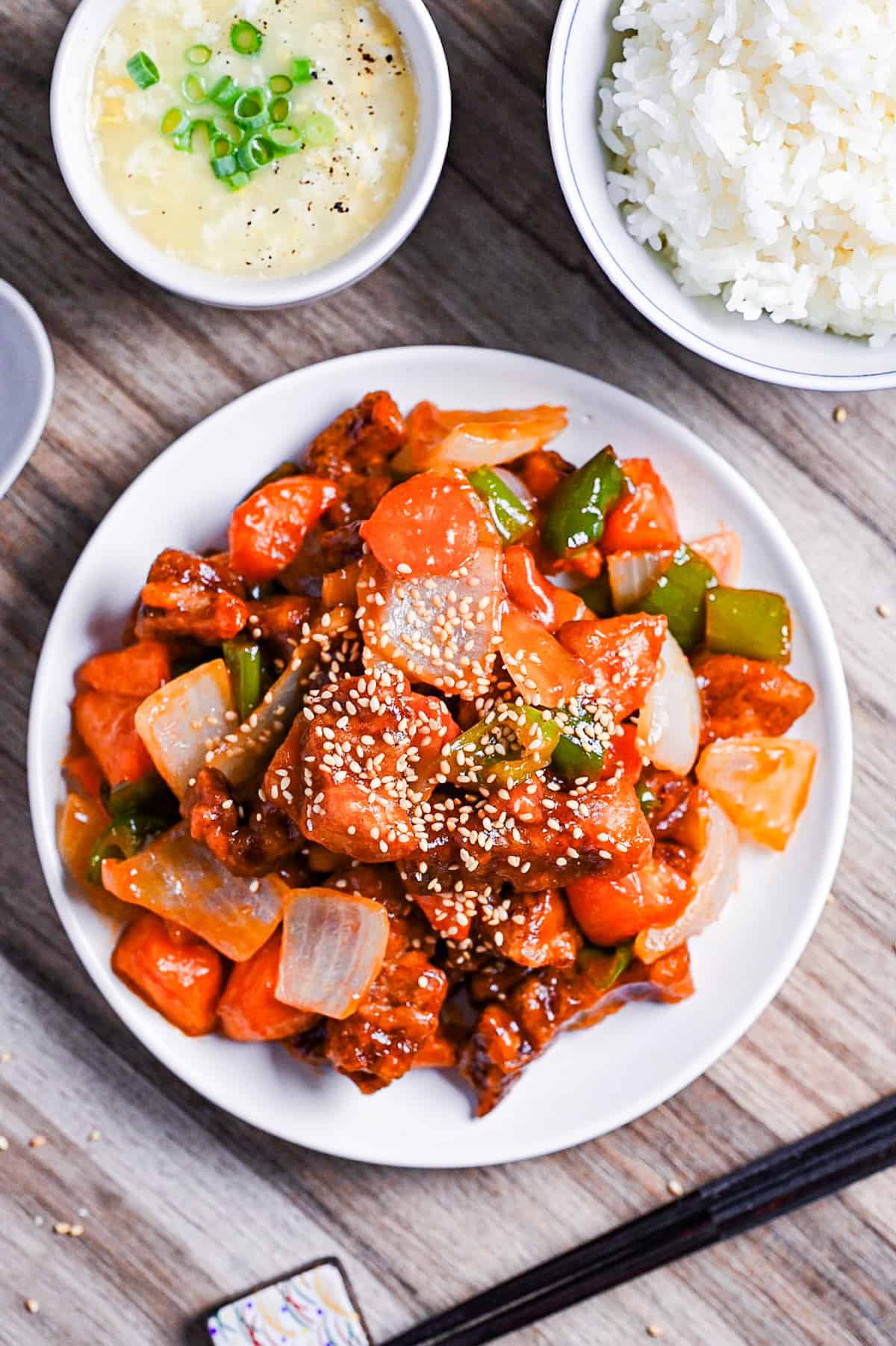 Subuta (Japanese sweet and sour pork) on a white plate served with egg soup and white rice