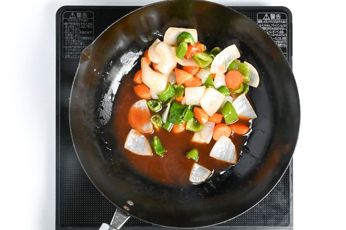 Fried onion, carrot and bell peppers in homemade sweet and sour subuta sauce in a wok