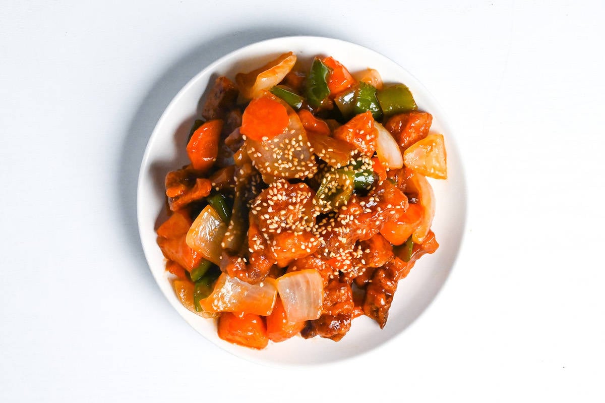 Subuta (Japanese sweet and sour pork) on a white plate sprinkled with sesame seeds