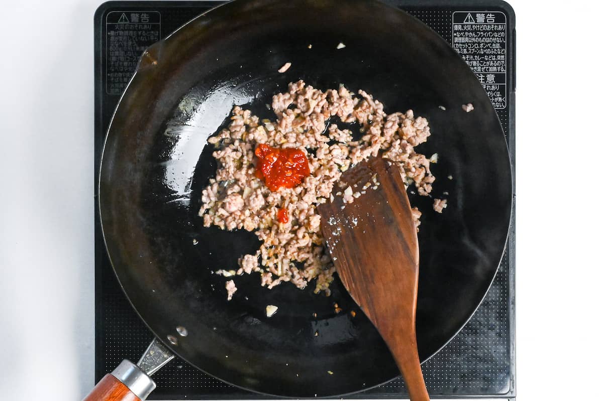 seasoning ground pork with Chinese chili bean paste in a wok