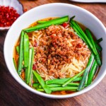 Nagoya style spicy Taiwan ramen in a white bowl, ramen noodles in a dashi based broth topped with garlic chive and spicy ground pork