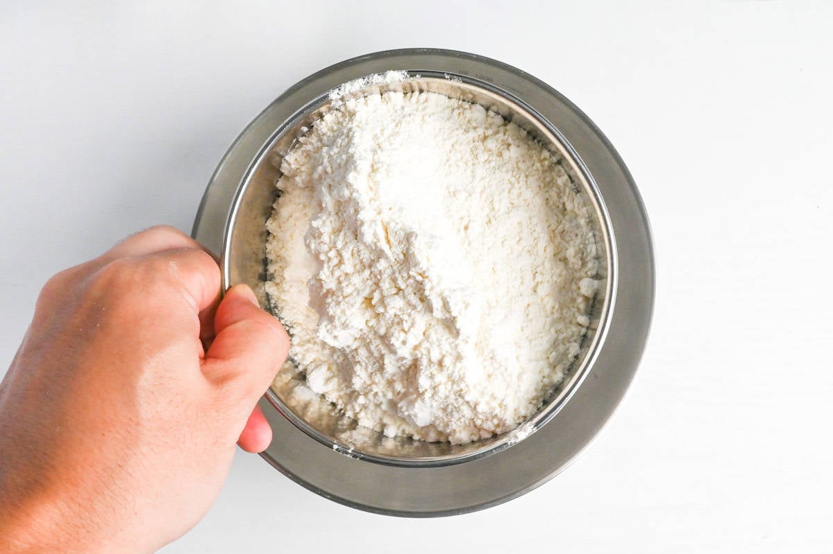 Sifting dry ingredients for tempura batter into a mixing bowl