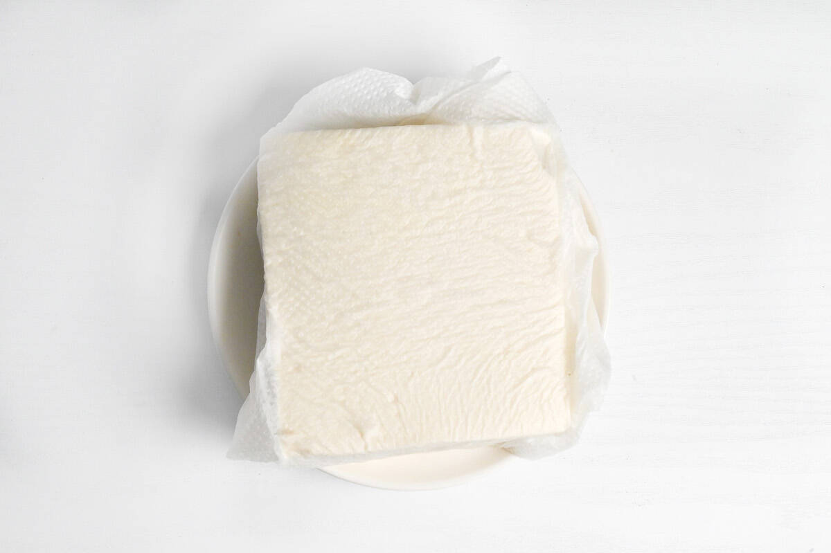 a block of firm tofu wrapped in kitchen paper