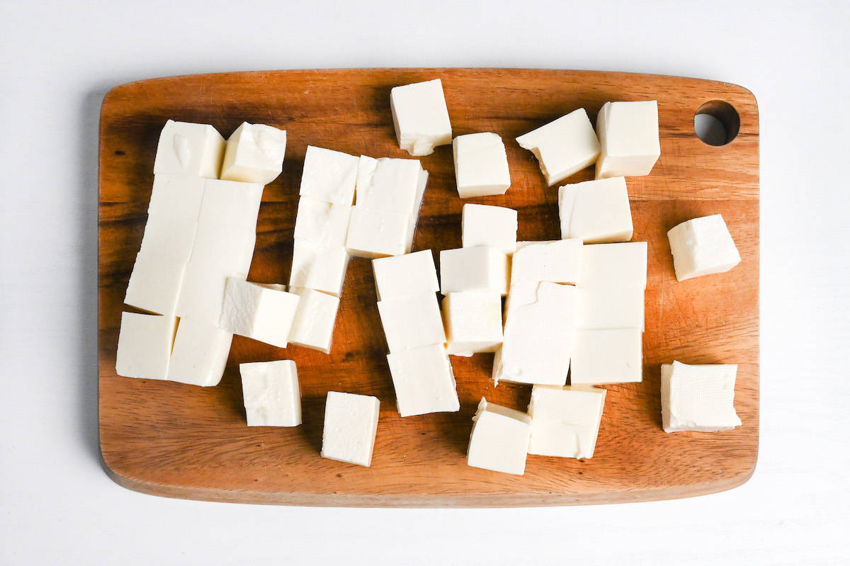 cubes of firm tofu on a wooden chopping board