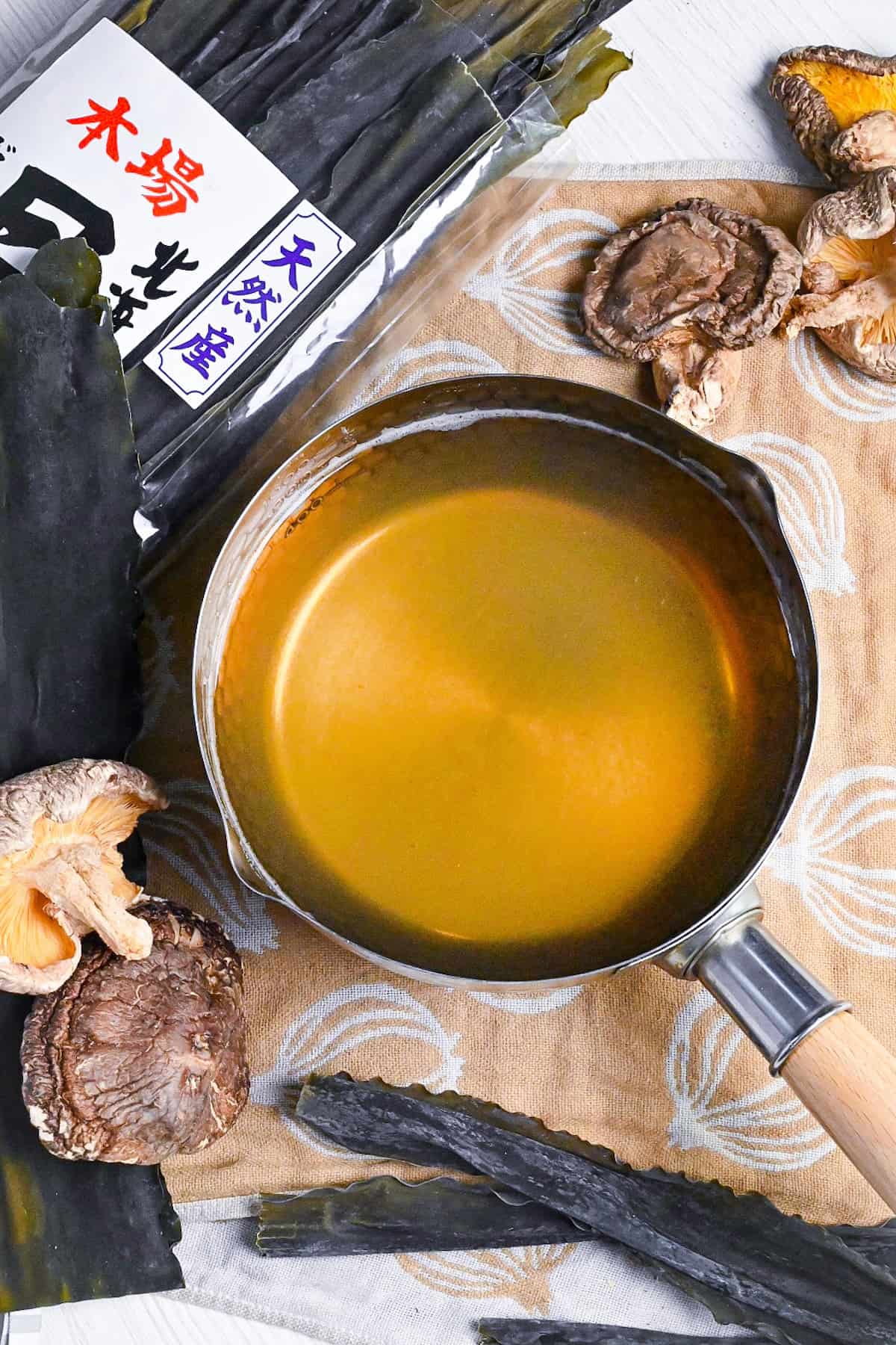 Vegan awase dashi made with kombu dried kelp and shiitake mushrooms in a steel pot