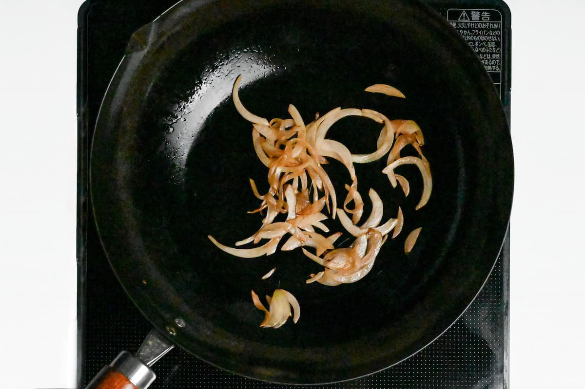 thinly sliced onion frying in a pan