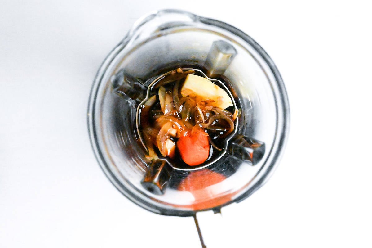 fried onion, apple, carrot, ginger and Japanese condiments in a glass blender