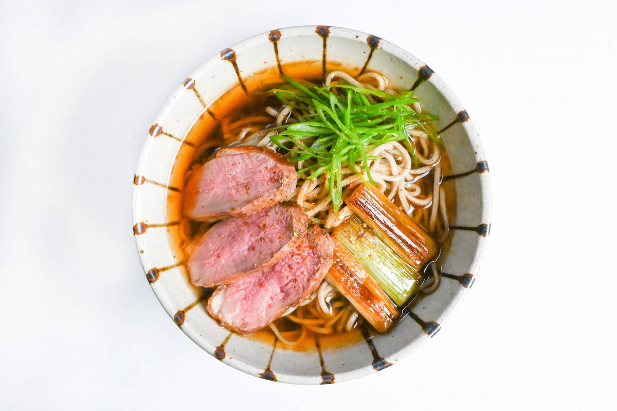 duck soba made with soba noodles in a hot dashi based broth and topped with charred green onions and slices of pan fried duck breast