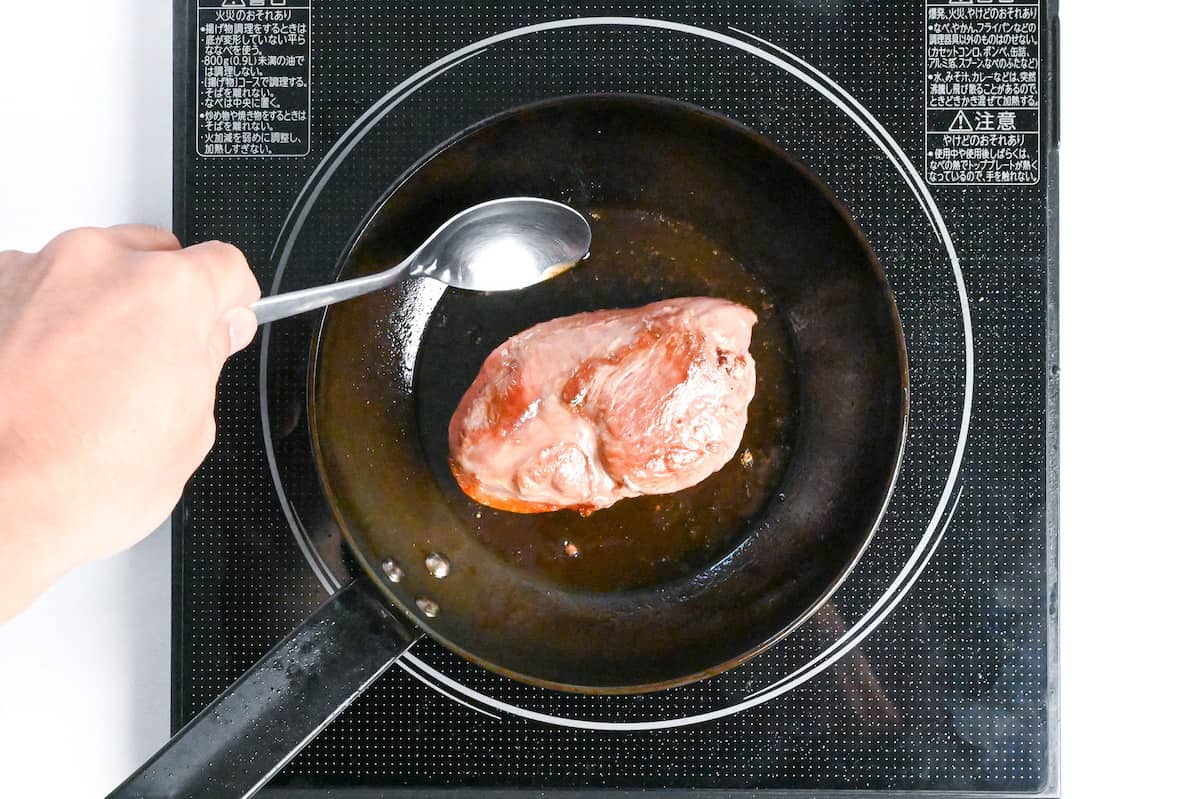 basting duck breast with leftover fat in a frying pan