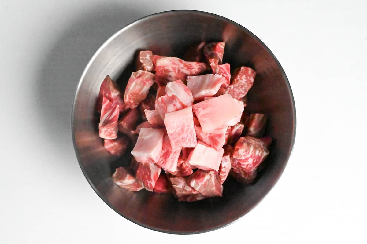 chunks of beef in a steel mixing bowl