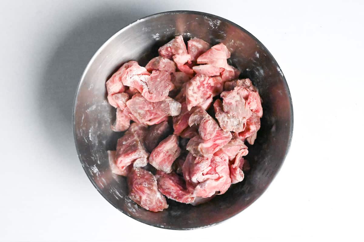 chunks of beef coated with flour in a mixing bowl