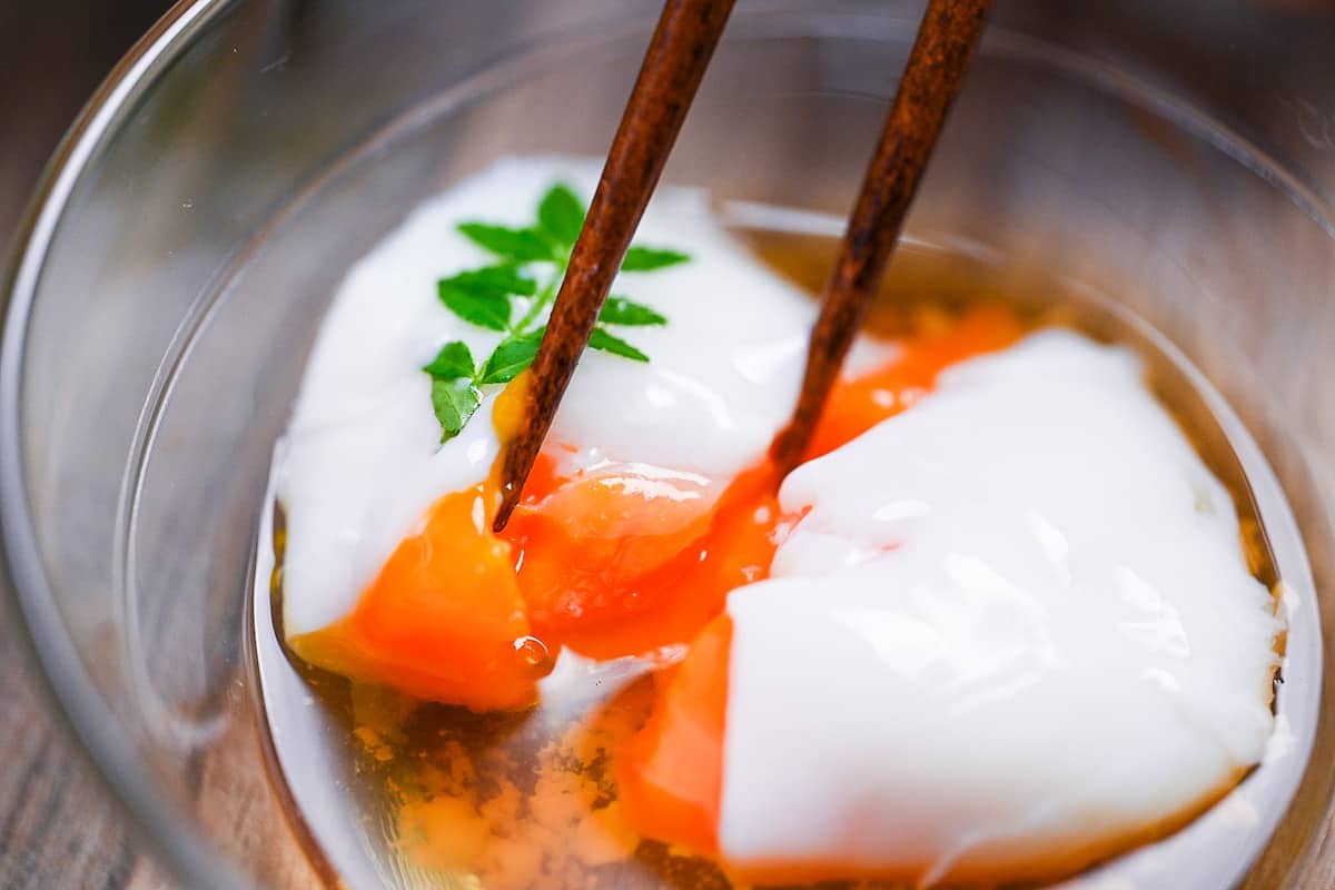 breaking apart onsen tamago (Japanese hot spring egg) with chopsticks to reveal silky yolk