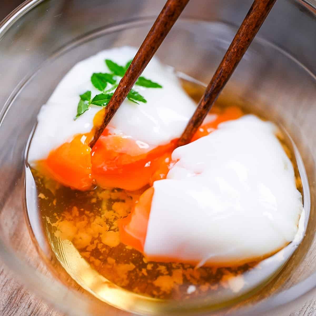 breaking apart onsen tamago (Japanese hot spring egg) with chopsticks to reveal silky yolk