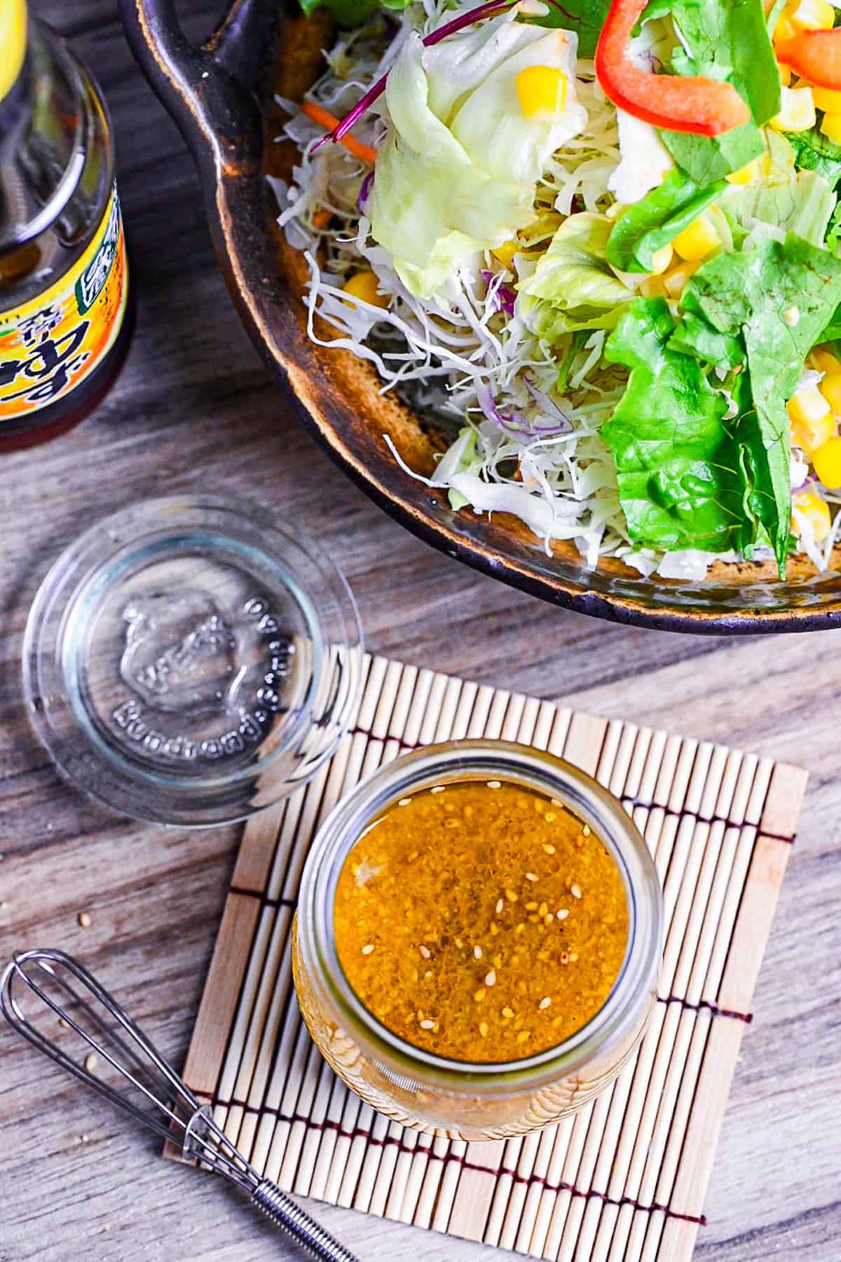 ponzu dressing in a glass jar next to a mixed leaf salad and bottle of yuzu ponzu