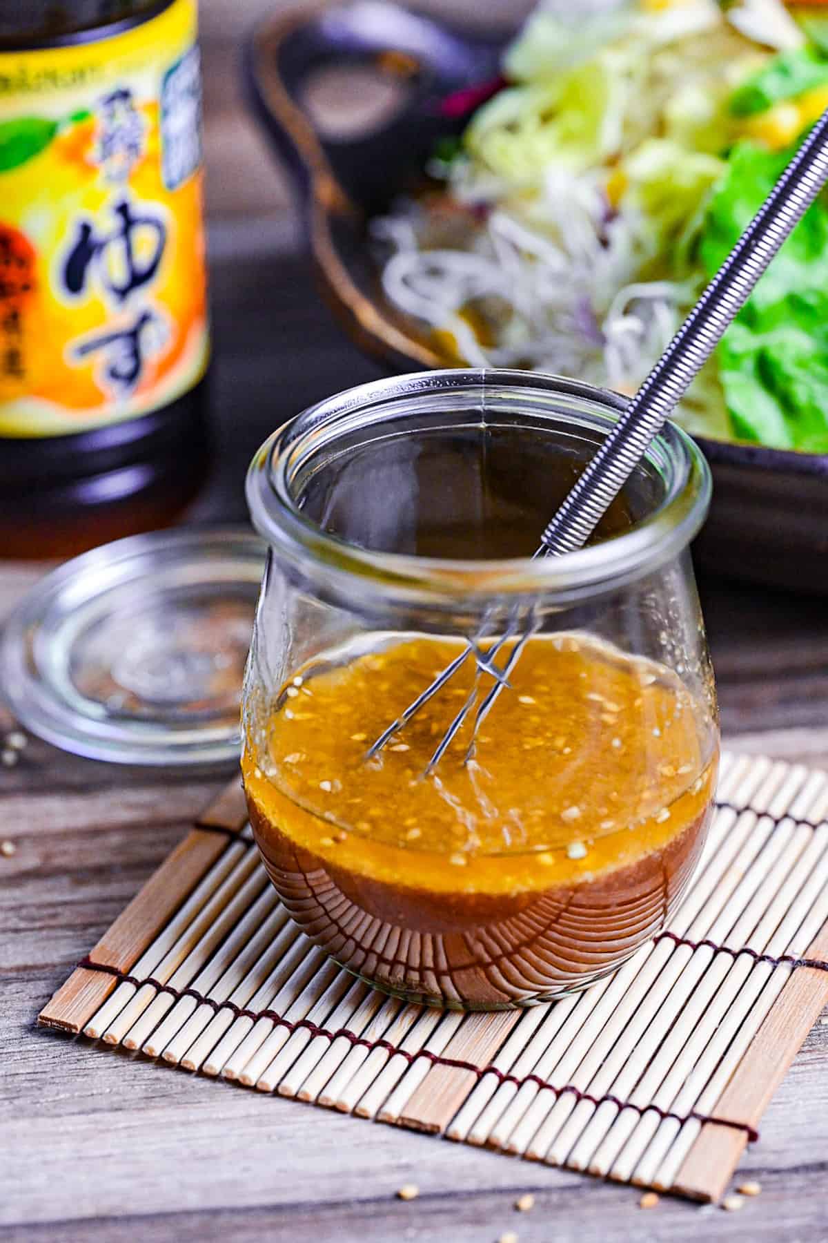 ponzu dressing in a glass jar next to a mixed leaf salad and bottle of yuzu ponzu