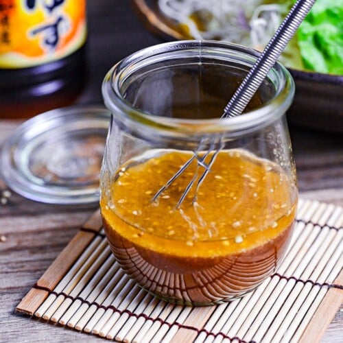 ponzu dressing in a glass jar next to a mixed leaf salad and bottle of yuzu ponzu