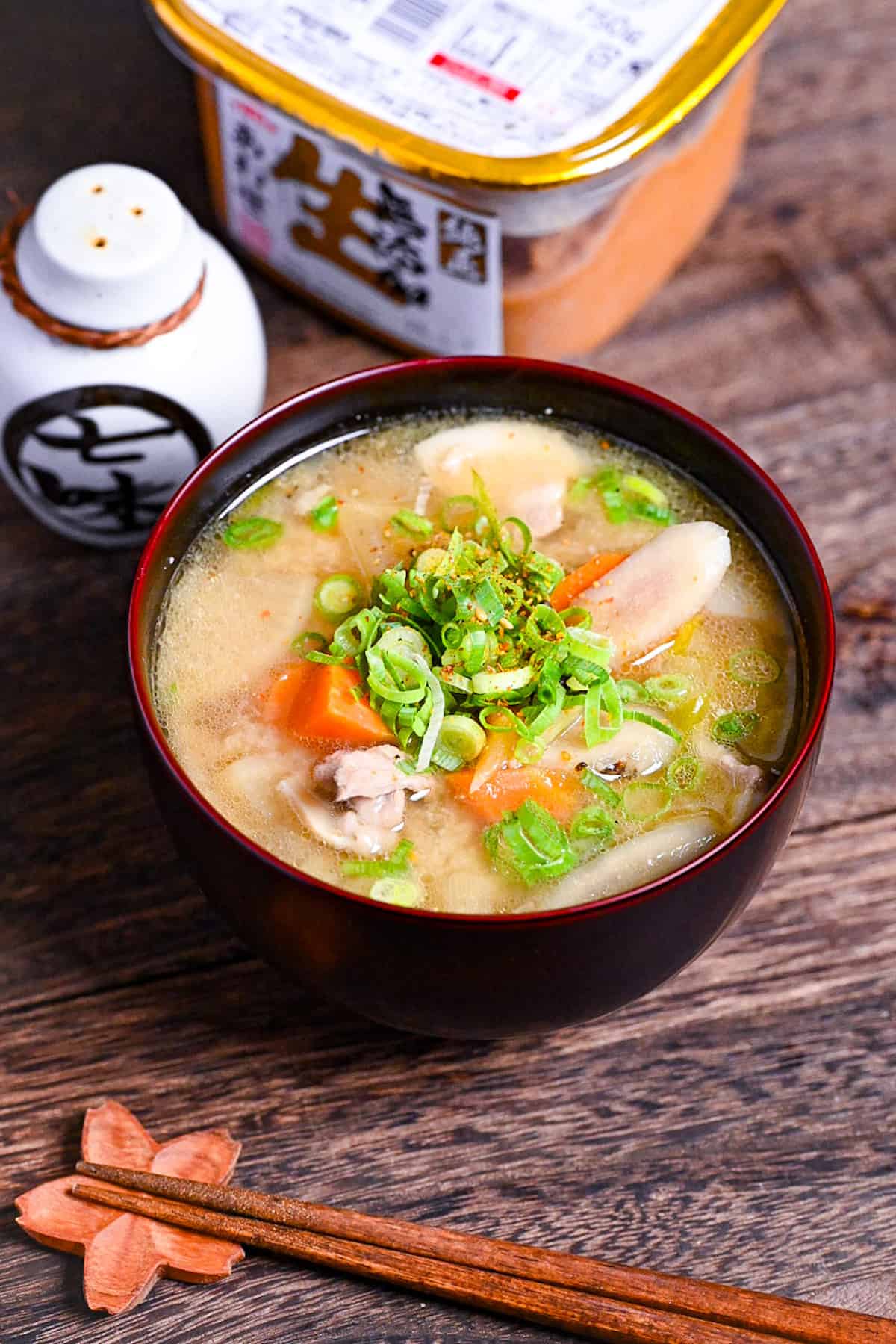 Japanese "Tonjiru" pork miso soup in a black and red bowl topped with shichimi togarashi (chili powder) and green onions