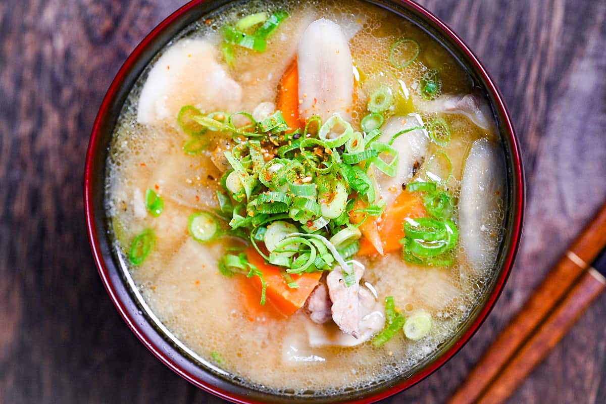 Japanese "Tonjiru" pork miso soup in a black and red bowl topped with shichimi togarashi (chili powder) and green onions