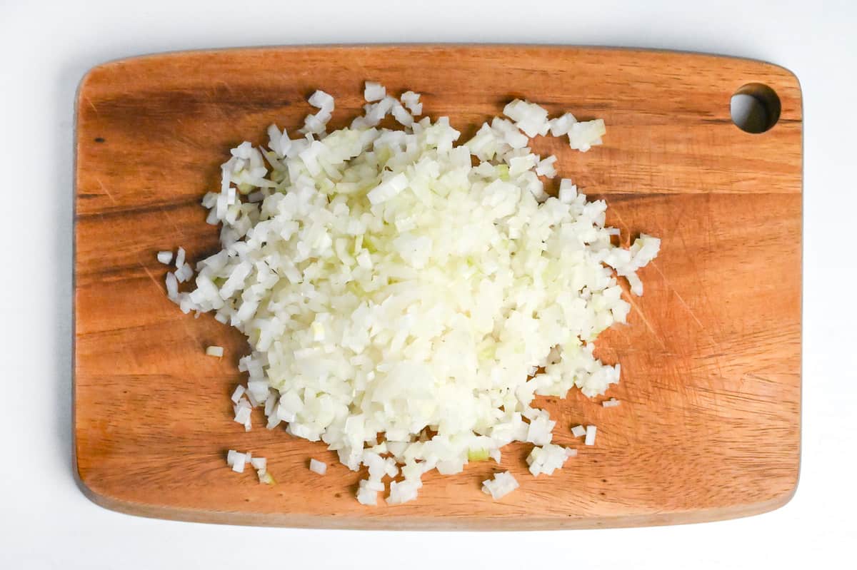 finely chopped onion on a wooden chopping board