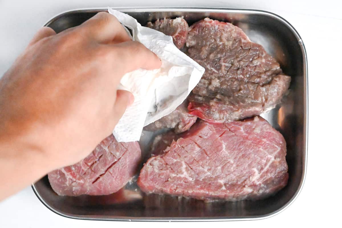 removing onion from steaks and patting dry with kitchen paper