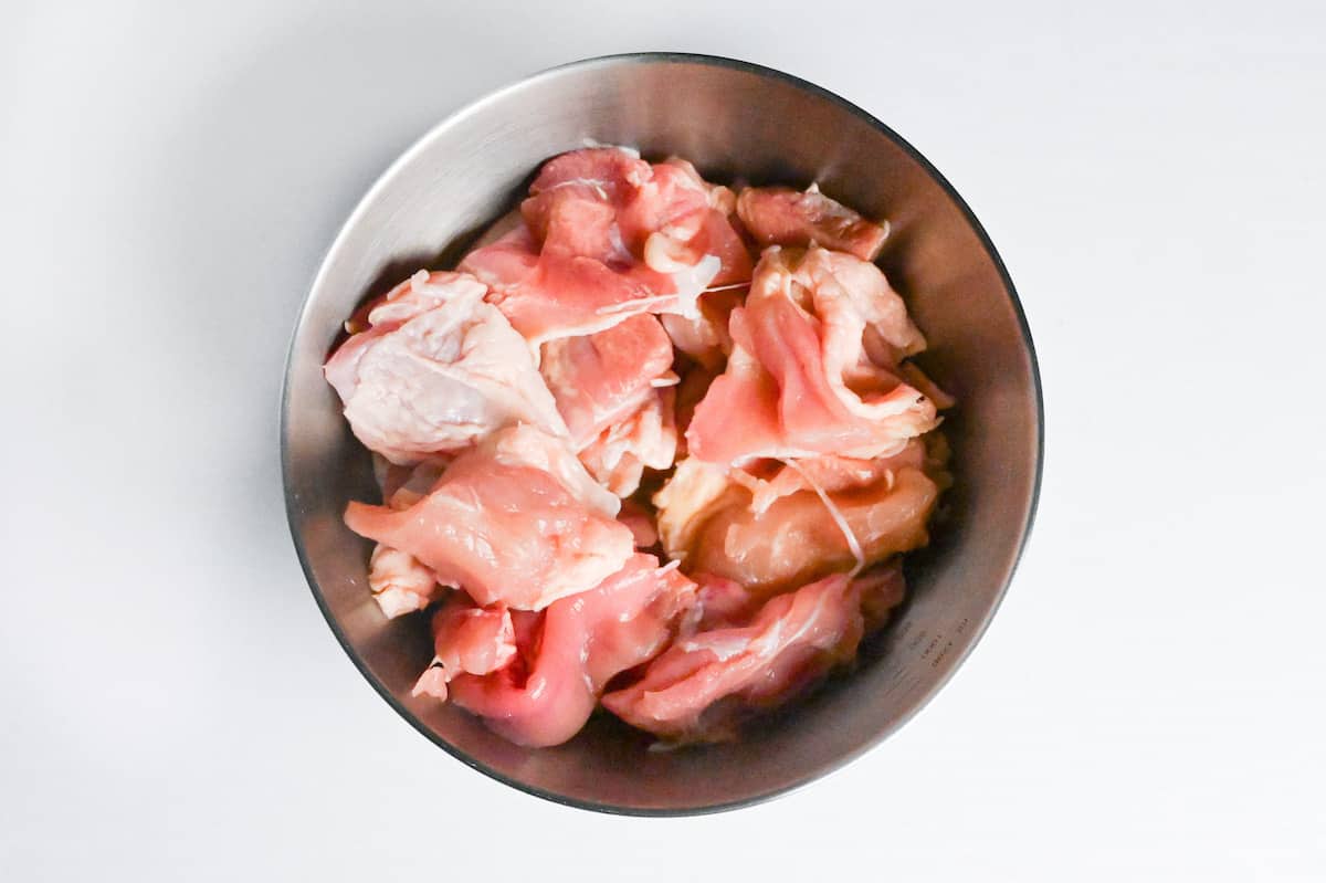 chicken thigh cut into pieces in a steel mixing bowl