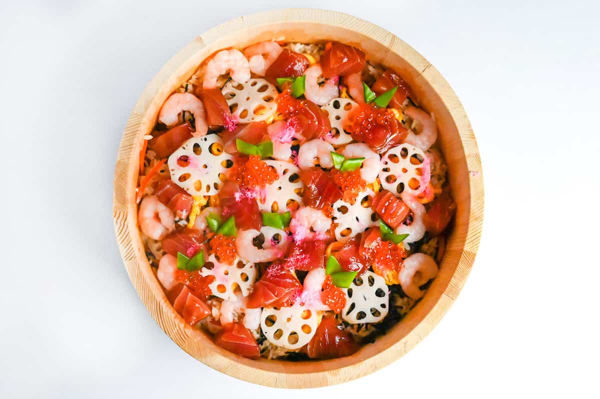 chirashizushi topped with slices of boiled lotus root, blanched snowpeas, marinated tuna, boiled shrimp and ikura (salmon roe)