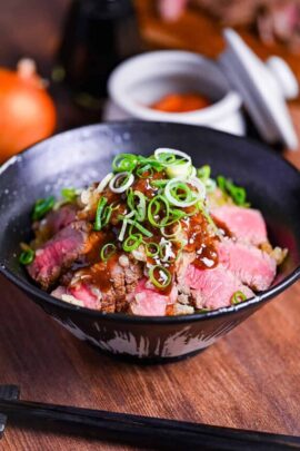 Chaliapin steak don made with slices of marinated steak cooked rare served over umeboshi and shiso rice and drizzled with an glossy gravy and chopped green onions