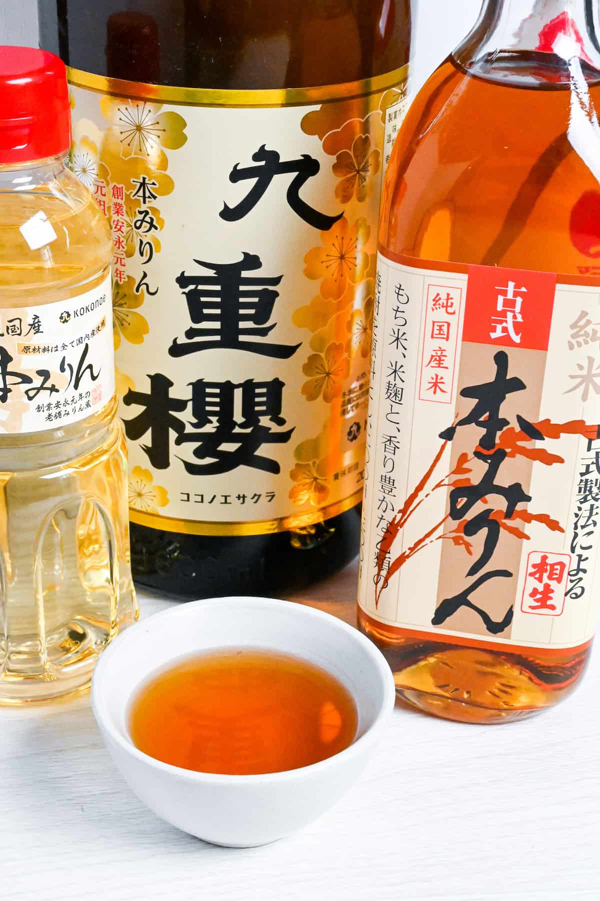 Bottles of Japanese hon mirin (Sweet rice wine seasoning) with some poured in a small white bowl