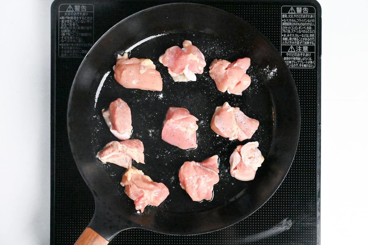 Bitesize pieces of chicken thigh frying in a pan