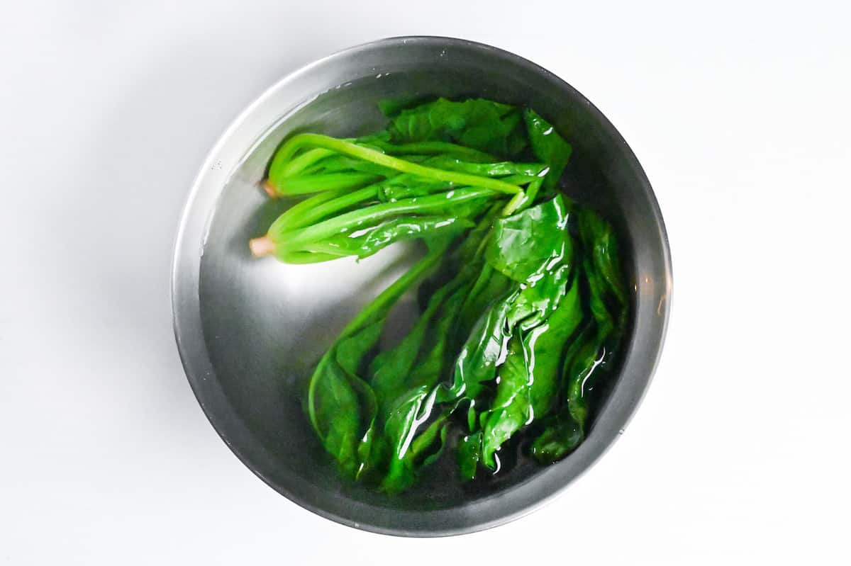 chilling blanched spinach in a bowl of cold water