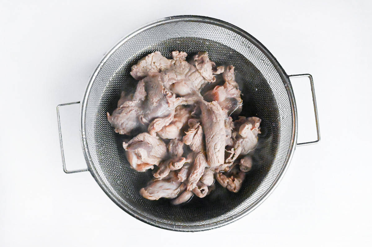 washed beef sinew in a sieve over a steel bowl